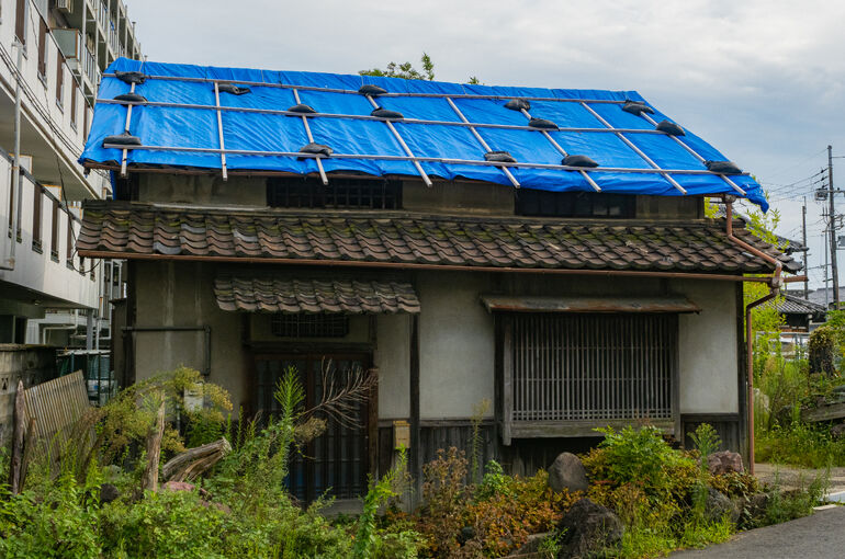 屋根が破損して応急処置をした住宅